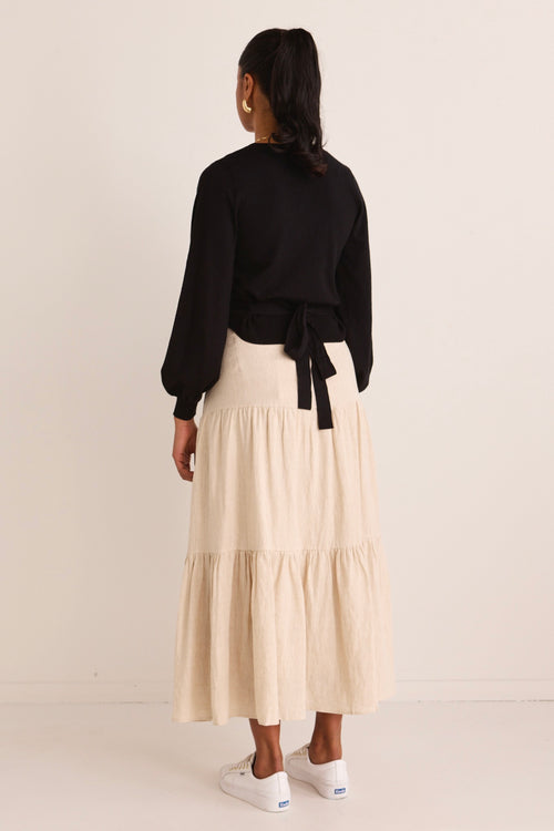 Model wears a beige tiered midi skirt with black top