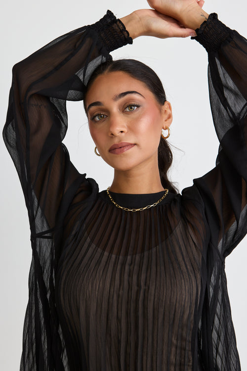 Model wears a black long sleeve blouse