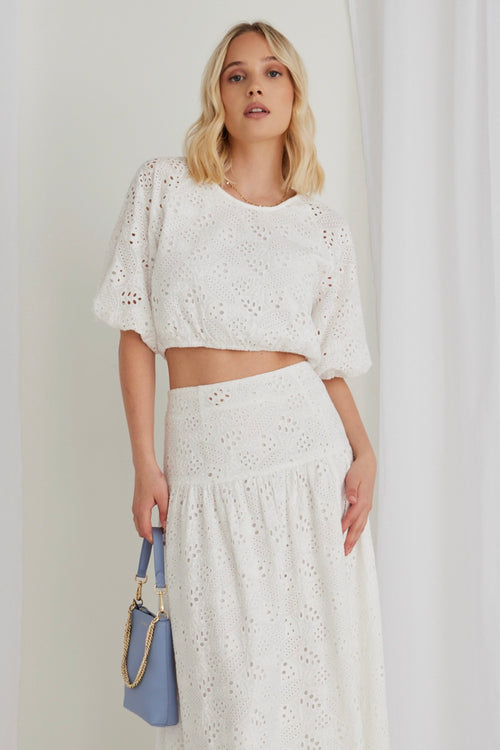 model in white top and matching white skirt