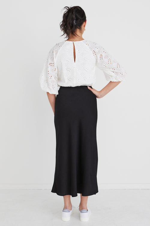model in white top and black skirt