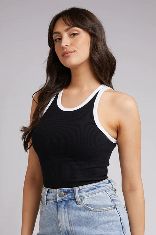 model in black tank with white lining and blue jeans