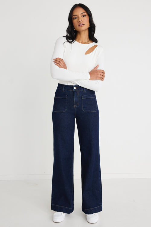 Model wears a white long sleeve top with jeans