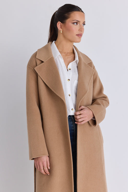 Model wears a brown beige coat with blue jeans