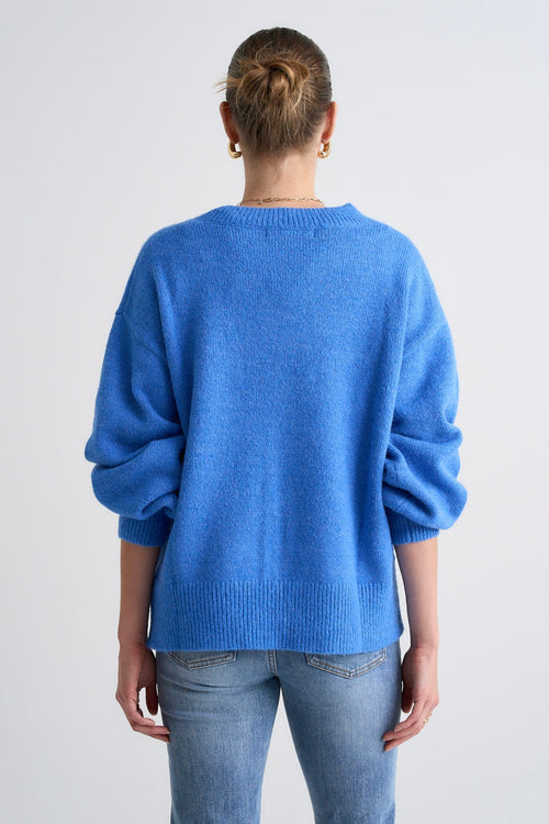 Model wears a blue jumper with jeans