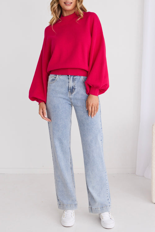 model wearing bright pink long sleeve jumper and light blue jeans and white sneakers