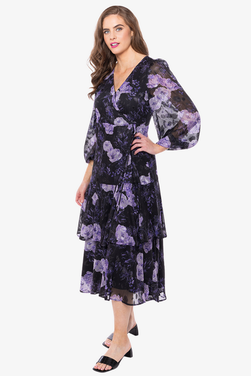 Model wearing black and purple floral long sleeve midi dress and black heels