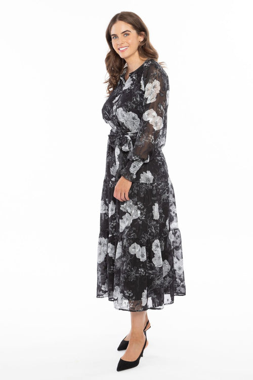 Model wearing long black and white floral maxi dress with black heels