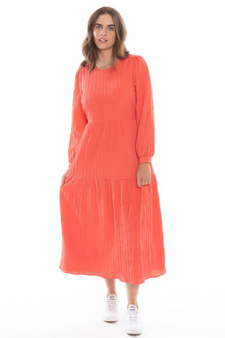 model posing in long sleeve orange maxi dress and white sneakers