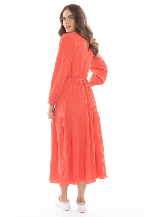 model posing in long sleeve orange maxi dress and white sneakers
