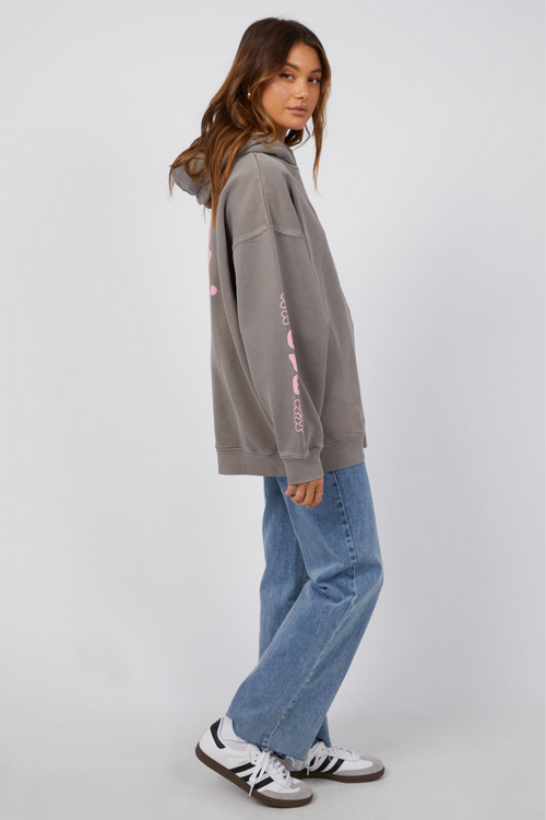 model wearing grey hoodie with pink lettering and blue jeans