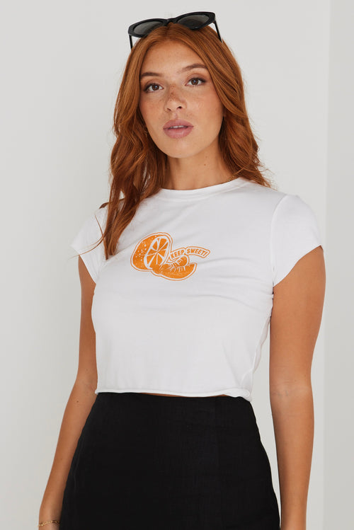 model wearing white crop top tee with an orange on the front and a black skirt