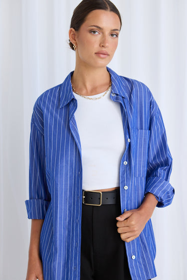 Model wears a blue stripe shirt with black pants