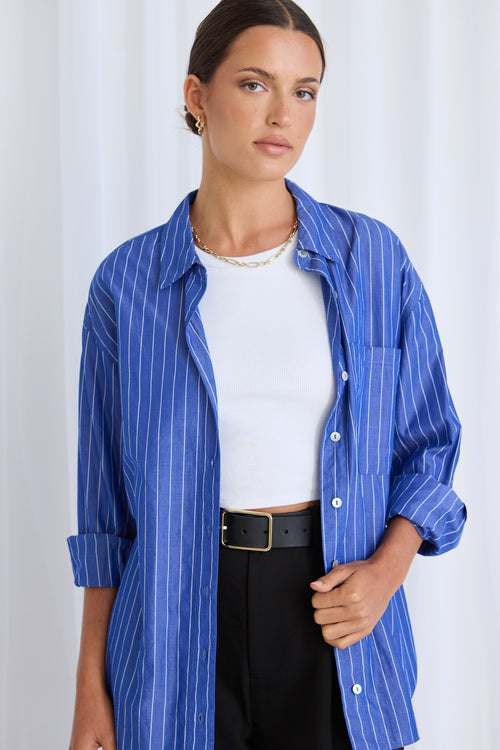 Model wears a blue stripe shirt with black pants